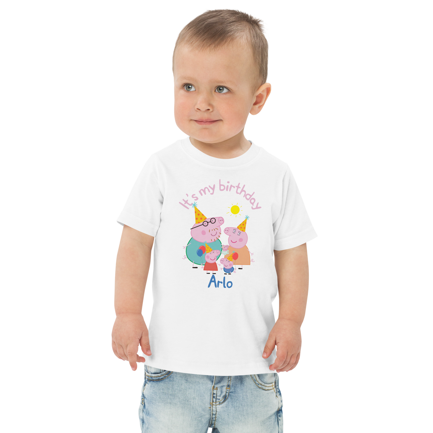 Close-up view of child's name printed in bold, playful font on the front of a Peppa Pig themed birthday shirt, surrounded by vibrant party graphics and cartoon characters