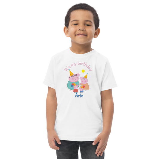 Little boy celebrating his birthday in a Peppa Pig themed shirt featuring cartoon-style characters, colourful bunting, and the phrase 'It's My Birthday' in bright letters