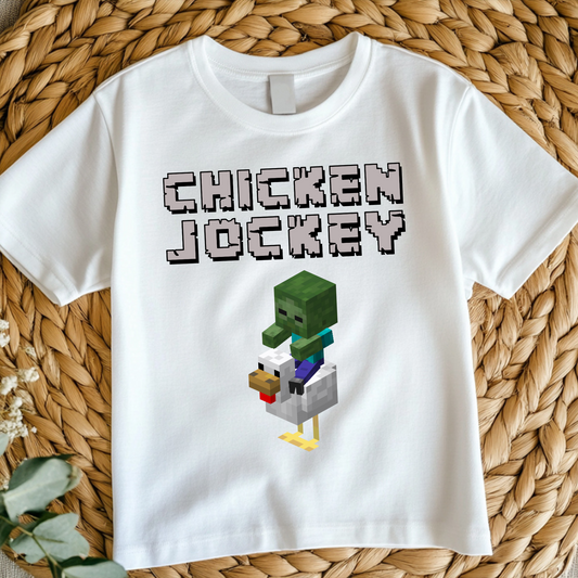 Kids white t-shirt featuring a pixelated chicken jockey graphic with a zombie riding a chicken, inspired by Minecraft.