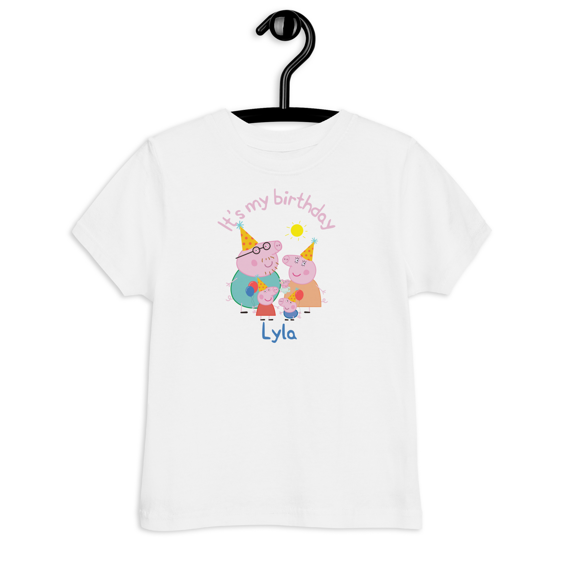 Young girl smiling while wearing a pink Peppa Pig birthday t-shirt customised with her name and festive design, standing in front of birthday decorations and balloons.